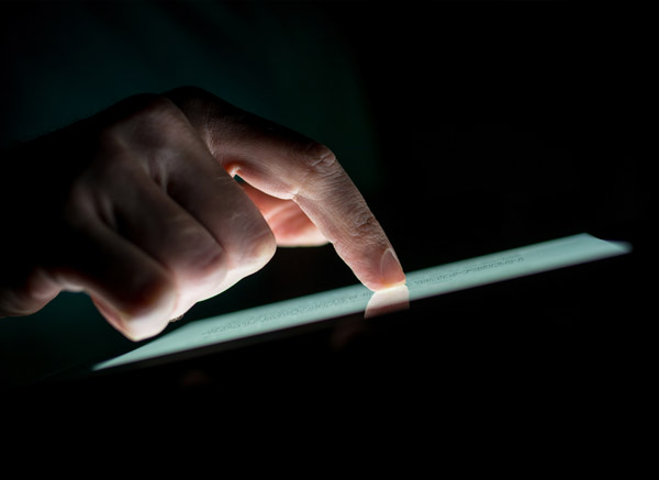 man touching tablet screen in dark